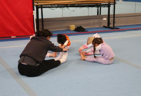 young girls stretching with teacher