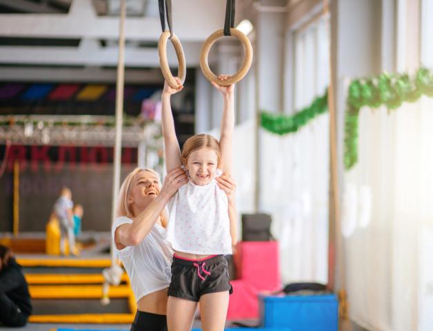 Image of child using gymnastics equipment and instructor 